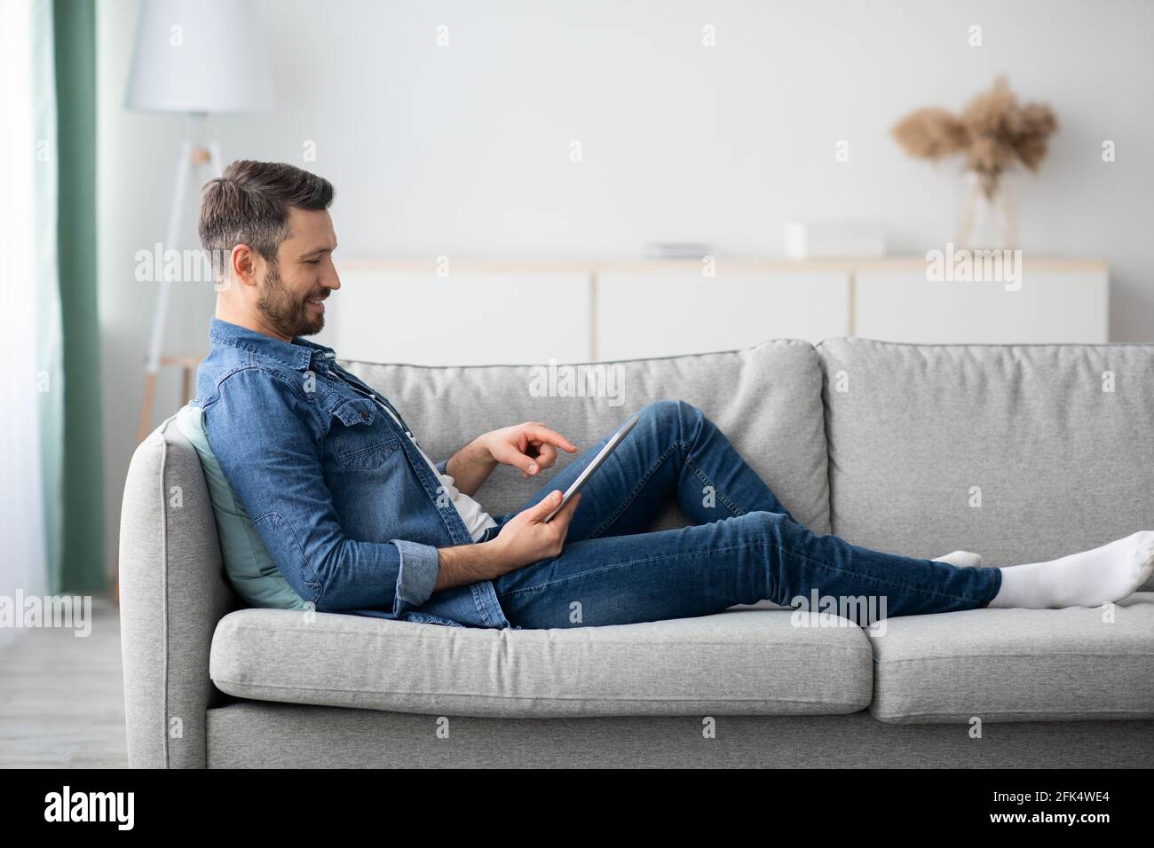 Uomo rilassato con la bearded che usa il tablet digitale a casa Foto Stock