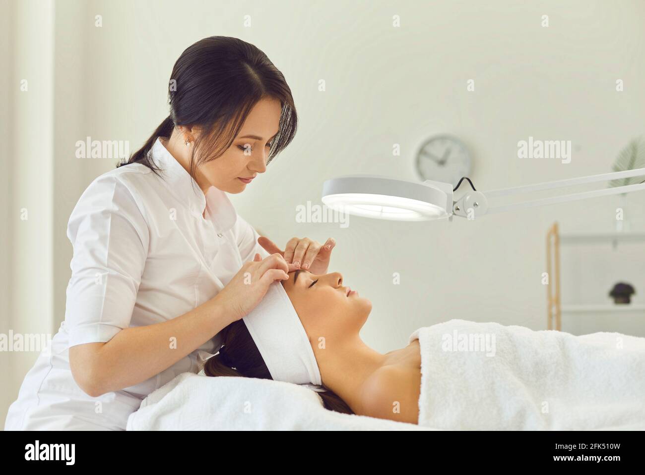 Donna dermatologa che tocca fronte donne durante l'esame della pelle Foto Stock