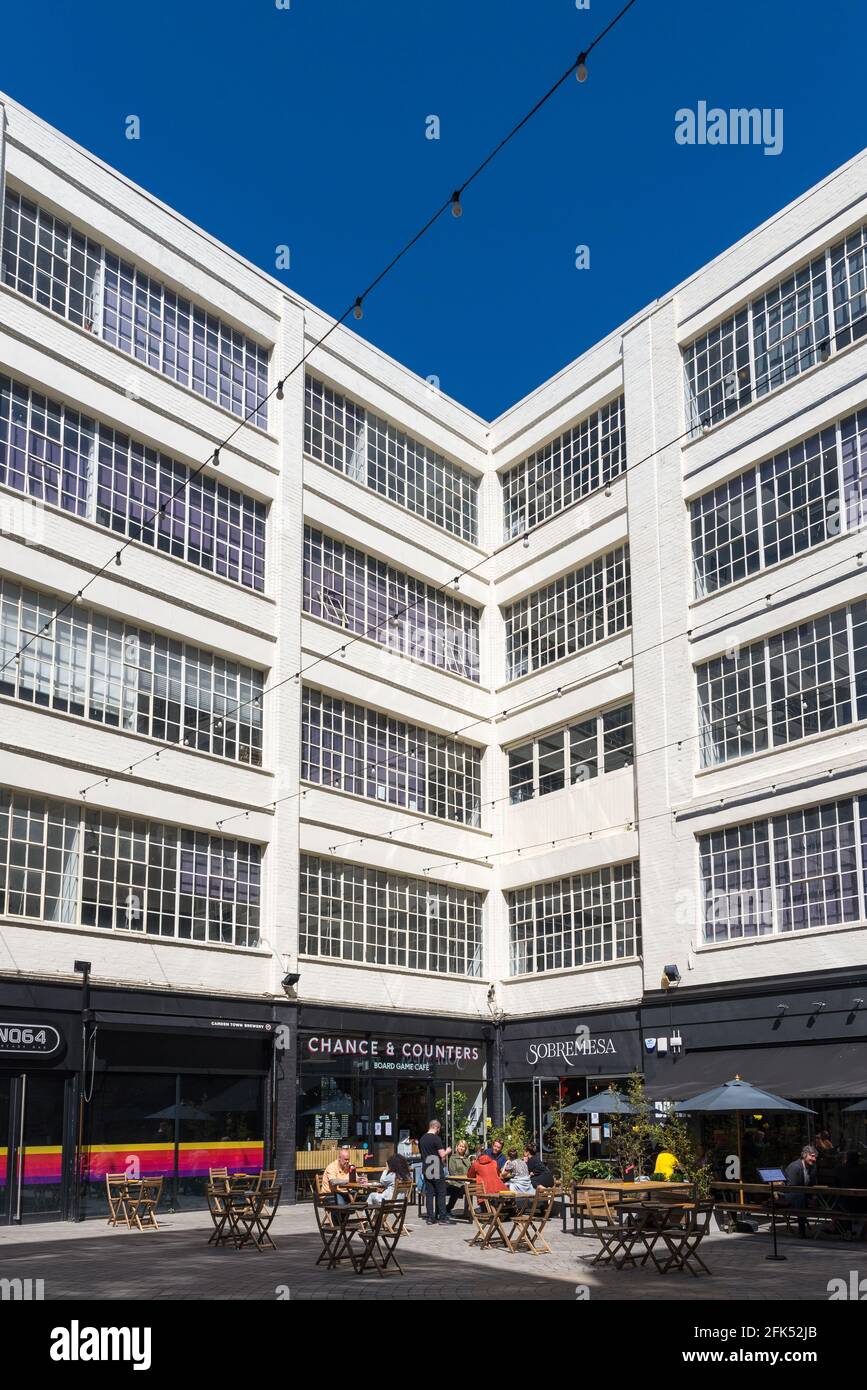 Persone che si siedono fuori mangiare e bere nel cortile nel quartiere creativo presso la Custard Factory a Digbeth, Birmingham, Regno Unito Foto Stock