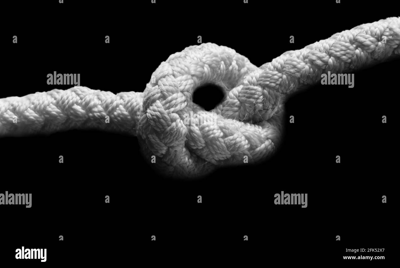 Nodo closeup su una corda su sfondo nero. Immagine orizzontale in bianco e nero. Foto Stock