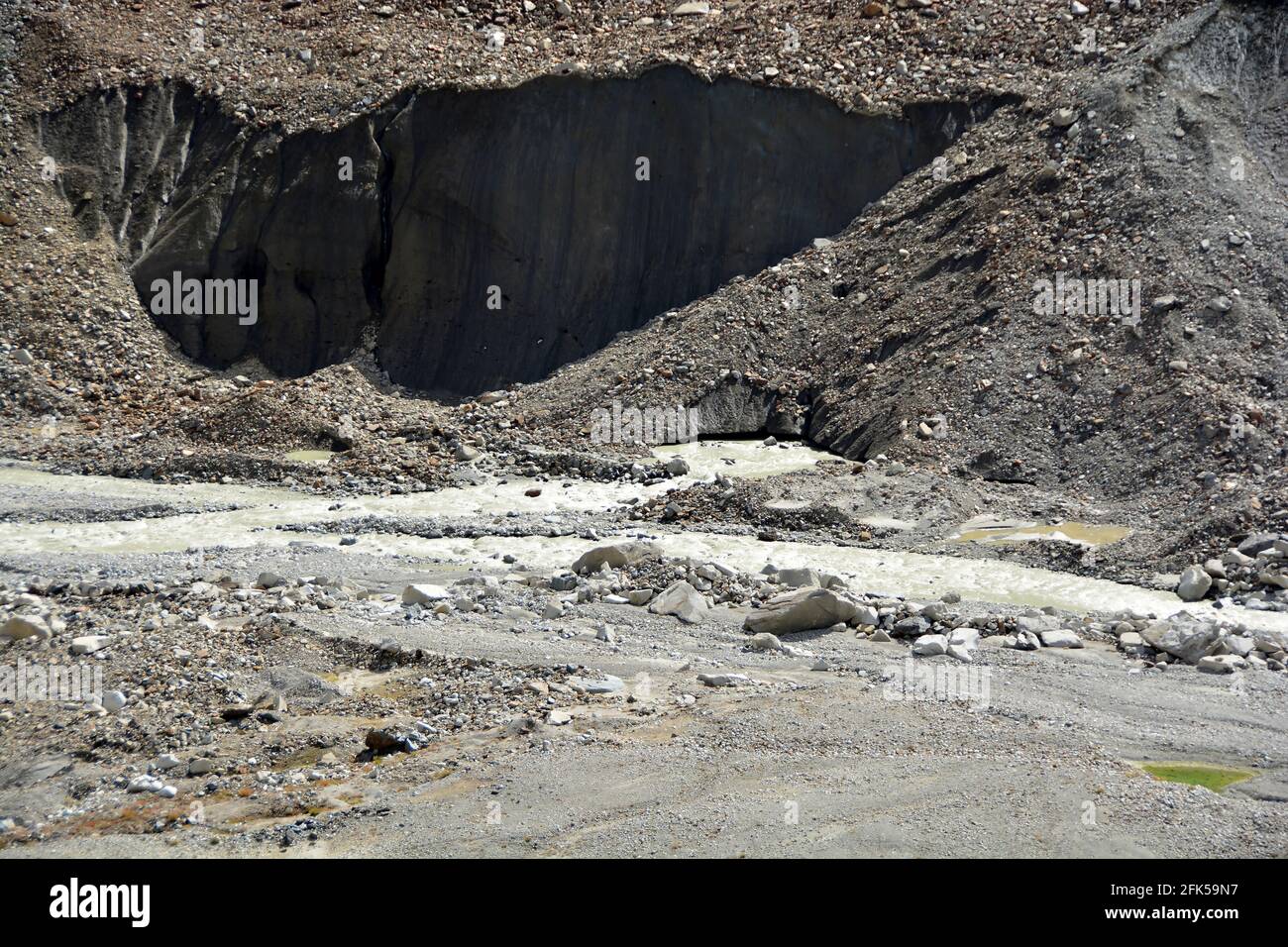 Il muso di un ghiacciaio che porta Morraine, con grandi blocchi di ghiaccio rotto e un fiume di acqua meltwater che scorre fuori Foto Stock