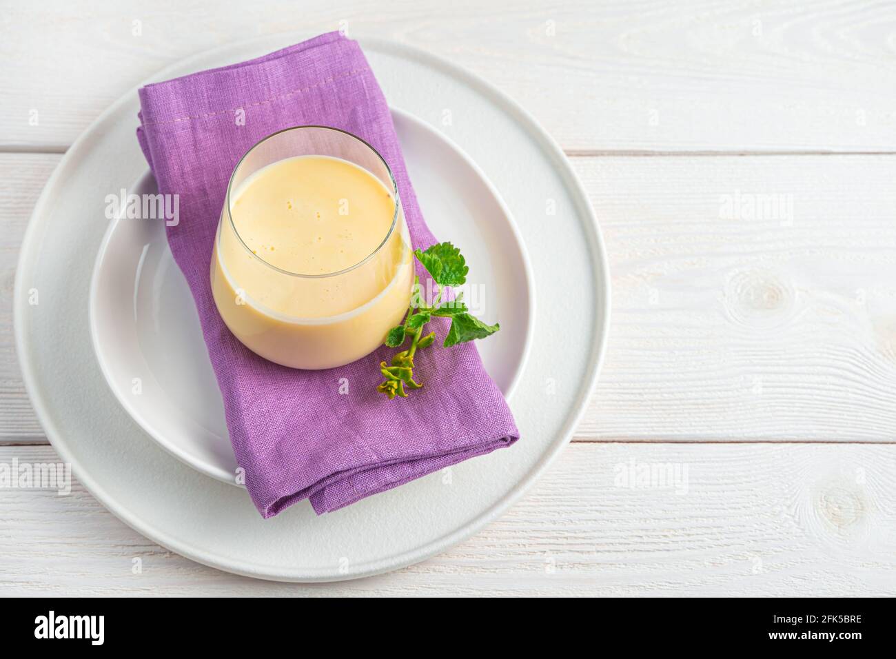Una bevanda fresca e fresca fatta di latte, yogurt, acqua e mango su uno sfondo chiaro. Foto Stock