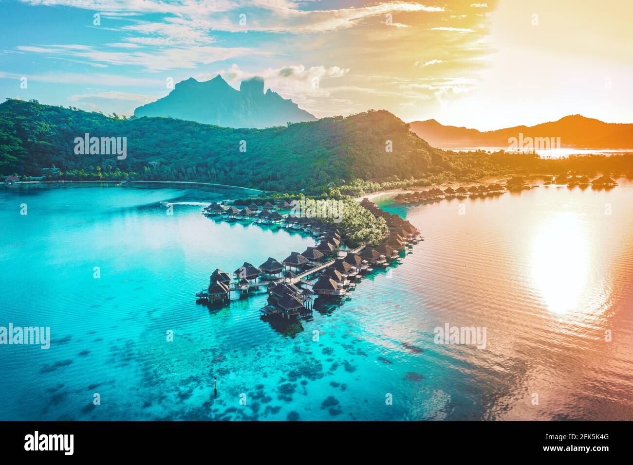 Viaggio aereo vacanza di lusso di overwater bungalow resort in corallo reef laguna oceano dalla spiaggia. Vista dall'alto al tramonto del paradiso fuga Bora Foto Stock