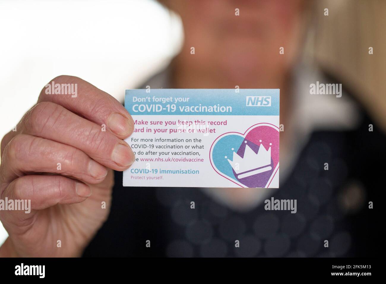 LONDRA, REGNO UNITO - APRILE 2021. Una persona in possesso della tessera NHS Covid-19 per la registrazione delle vaccinazioni Foto Stock