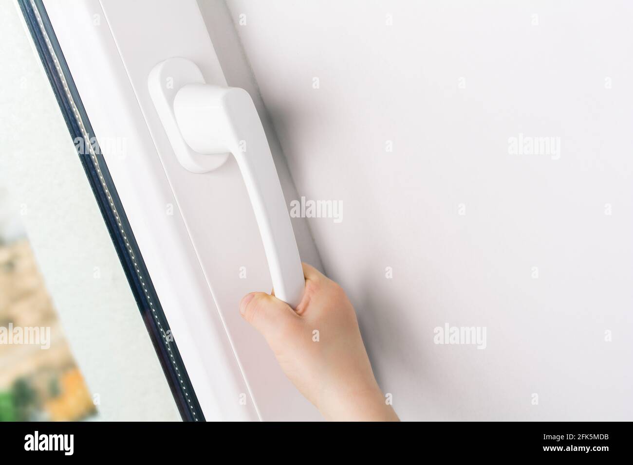 Mano figlio che tenta di aprire un handle di finestra di A. Finestra bianca chiusa - concetto di prevenzione del rischio per bambini Foto Stock