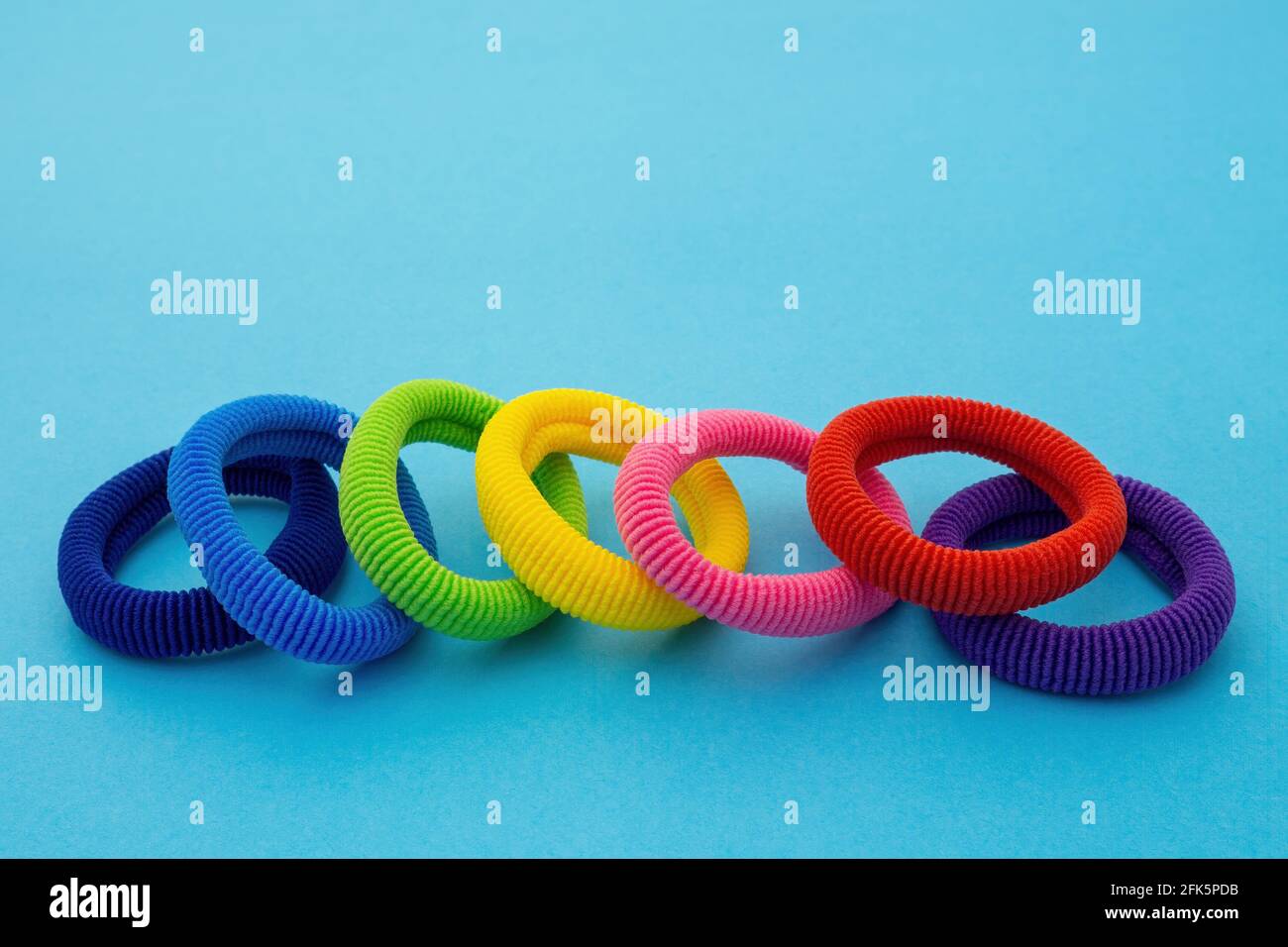 Scrunchies, cravatte elasticizzate colorate, supporti per coda di rondine per bambini in cotone, fasce per capelli senza cuciture su sfondo blu. Foto Stock