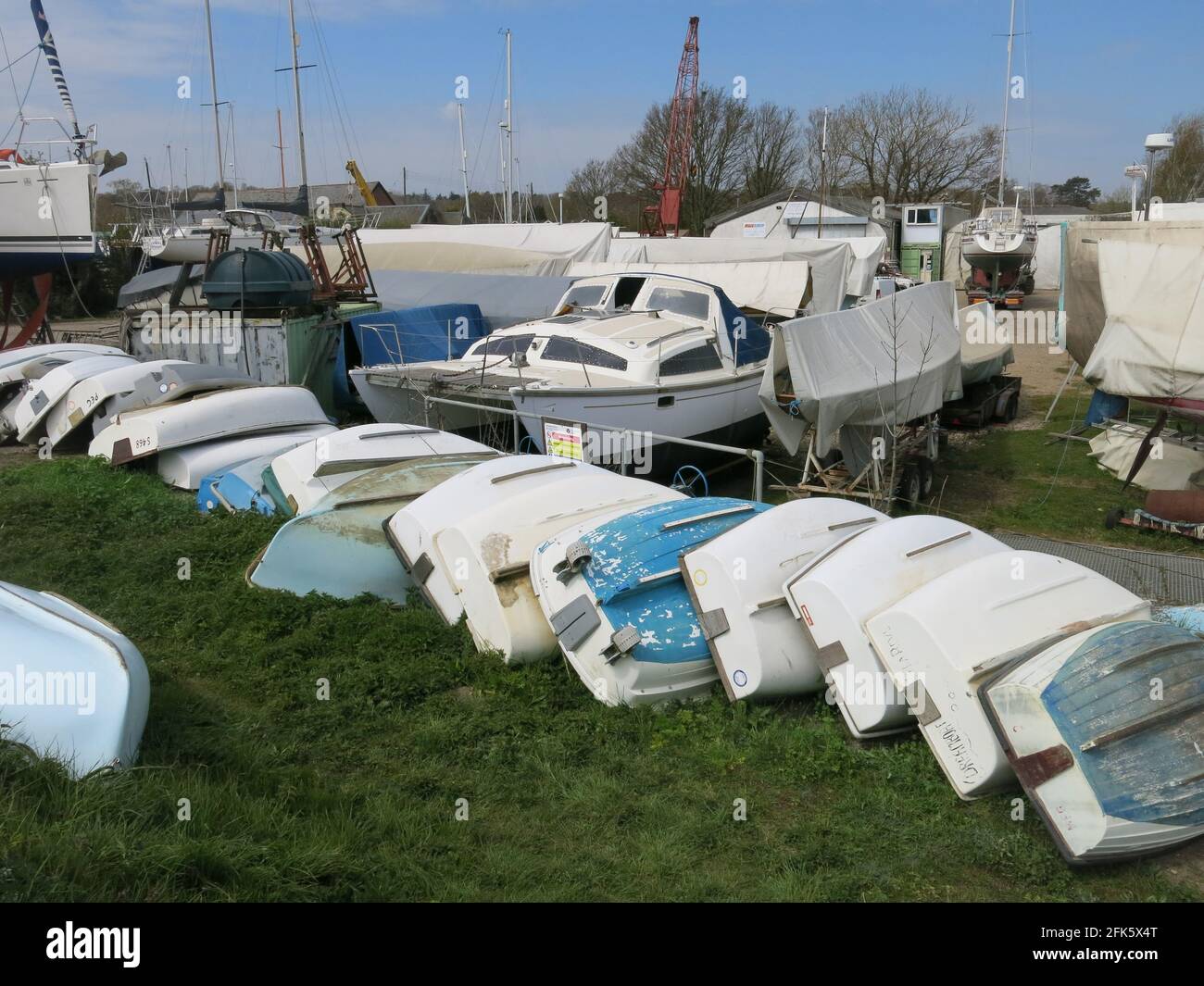 Una fila di gommoni ribaltati in deposito presso il cantiere di Melton sul fiume Deben, dove ci sono impianti di attracco a secco per la riparazione e la manutenzione degli yacht. Foto Stock