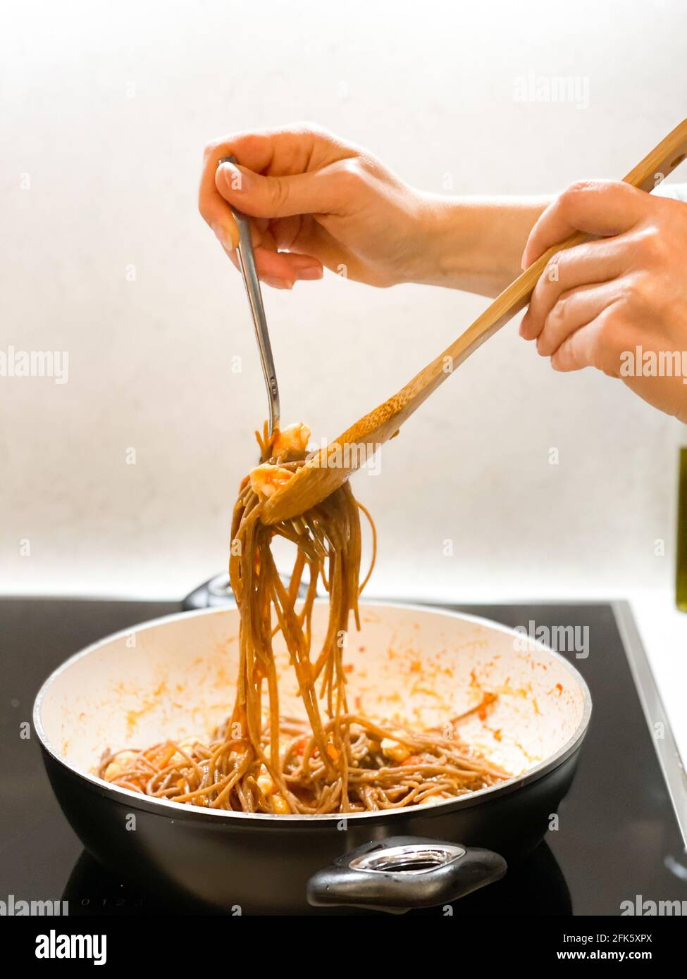 Primo piano le mani femminili cucinare la pasta con i frutti di mare, senza viso. Foto Stock