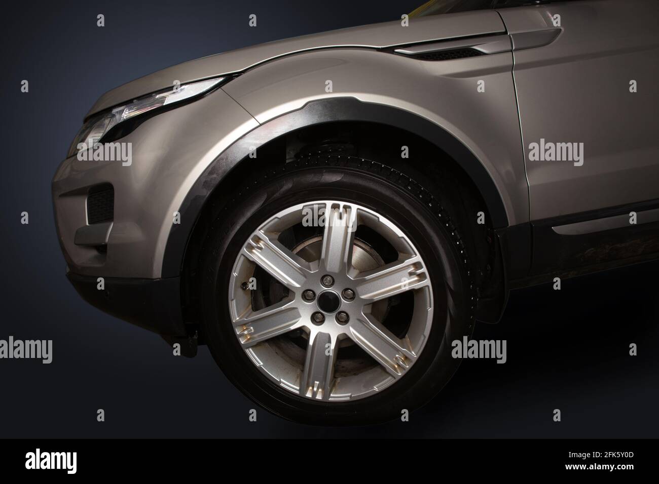 Cofano e pneumatici di un'auto moderna. Primo piano. Isolato su sfondo scuro. Vista laterale. Foto Stock