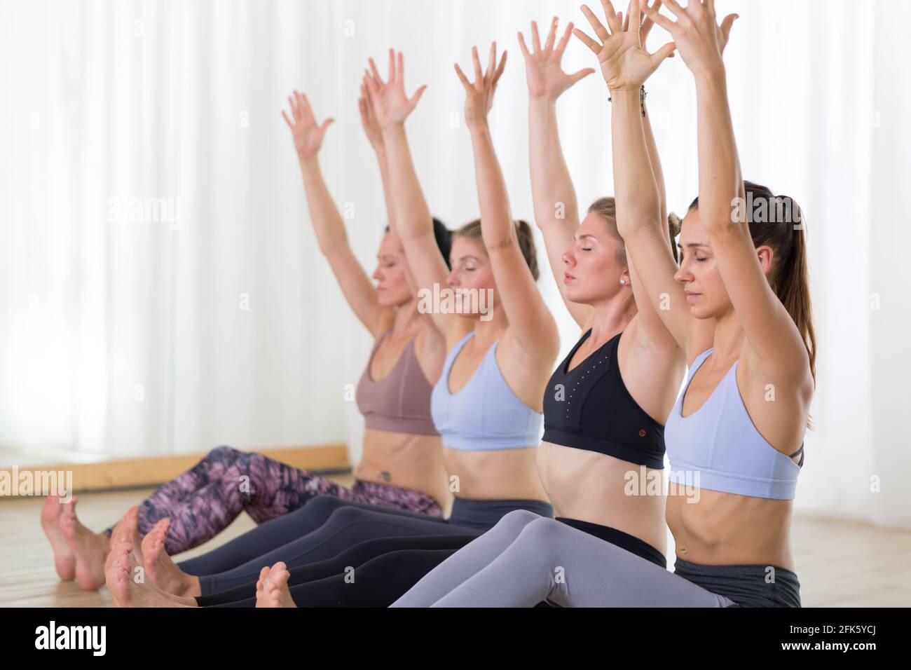Gruppo di giovani donne sportive attraenti in studio di yoga, pratica lezione di yoga con istruttore. Foto Stock