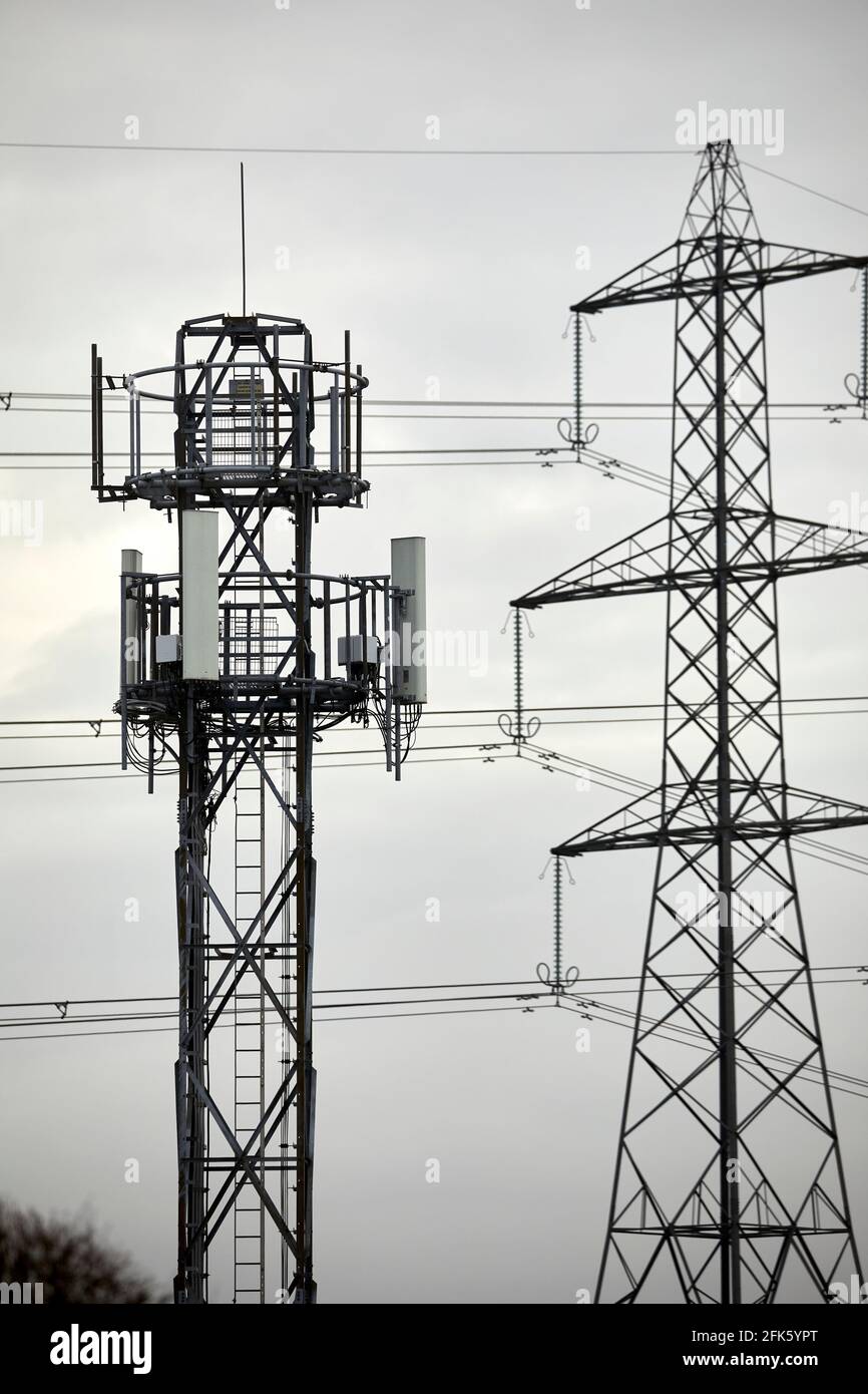 Primo piano di un palo di telefono della rete cellulare con silhouette e. traliccio elettrico torre pilone Foto Stock