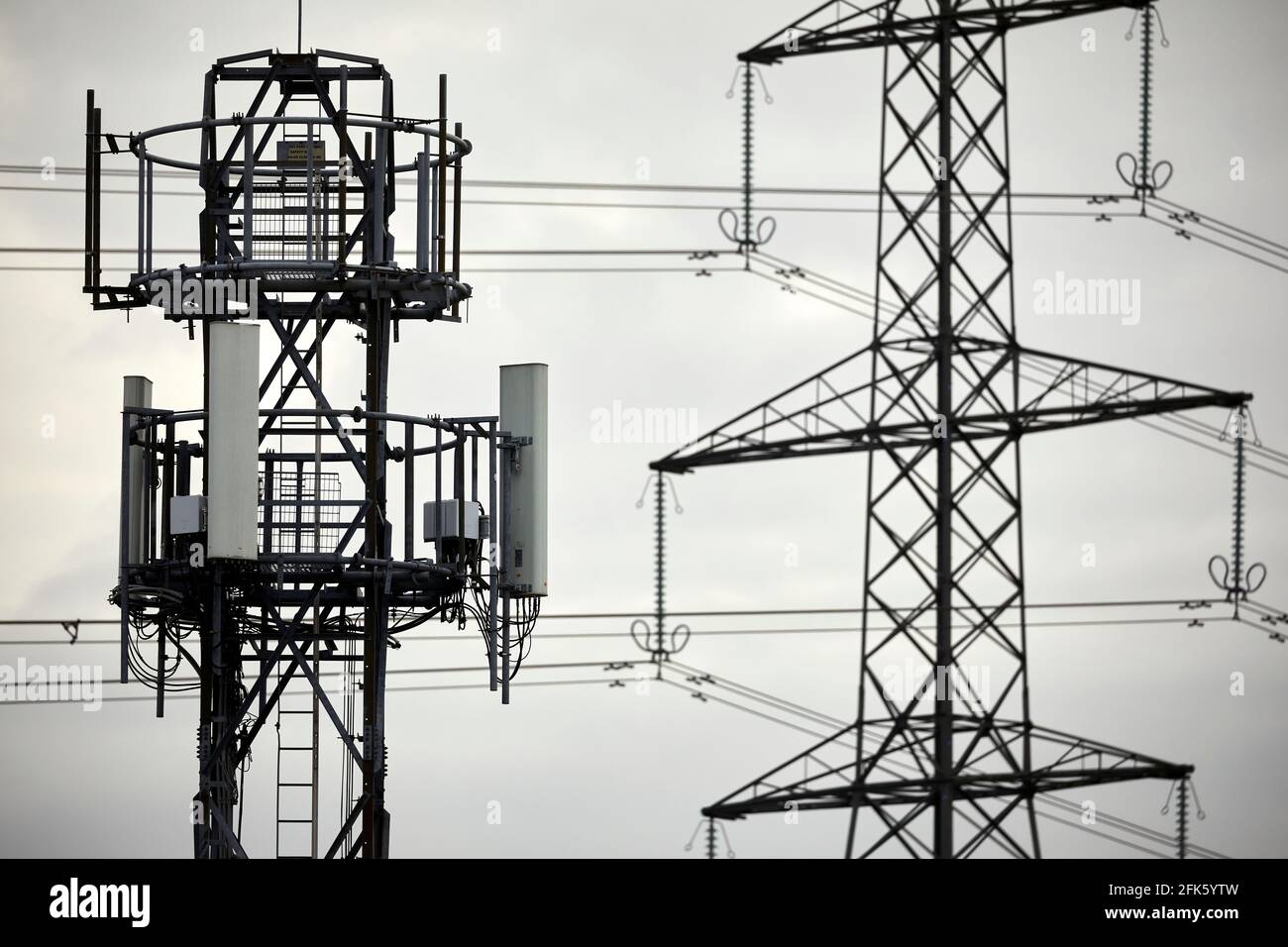 Primo piano di un palo di telefono della rete cellulare con silhouette e. traliccio elettrico torre pilone Foto Stock