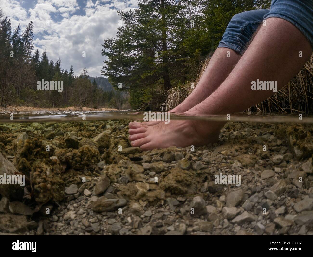 Piedi rinfrescanti escursionisti nel freddo fiume di montagna Foto Stock