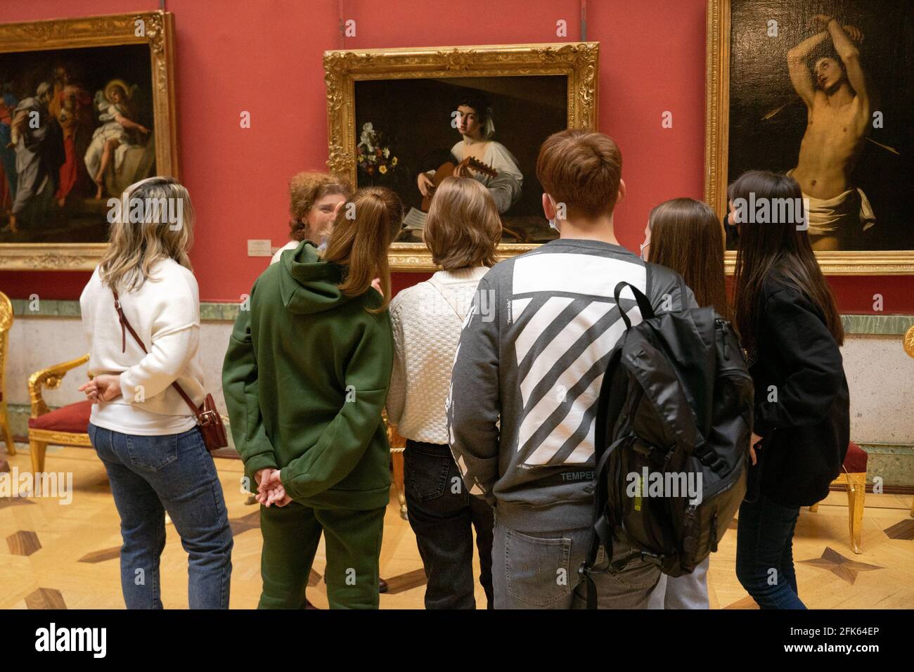La guida del tour parla con un gruppo di visitatori del dipinto di Caravaggio "Lute Player" nel museo Hermitage, San Pietroburgo, Russia Foto Stock