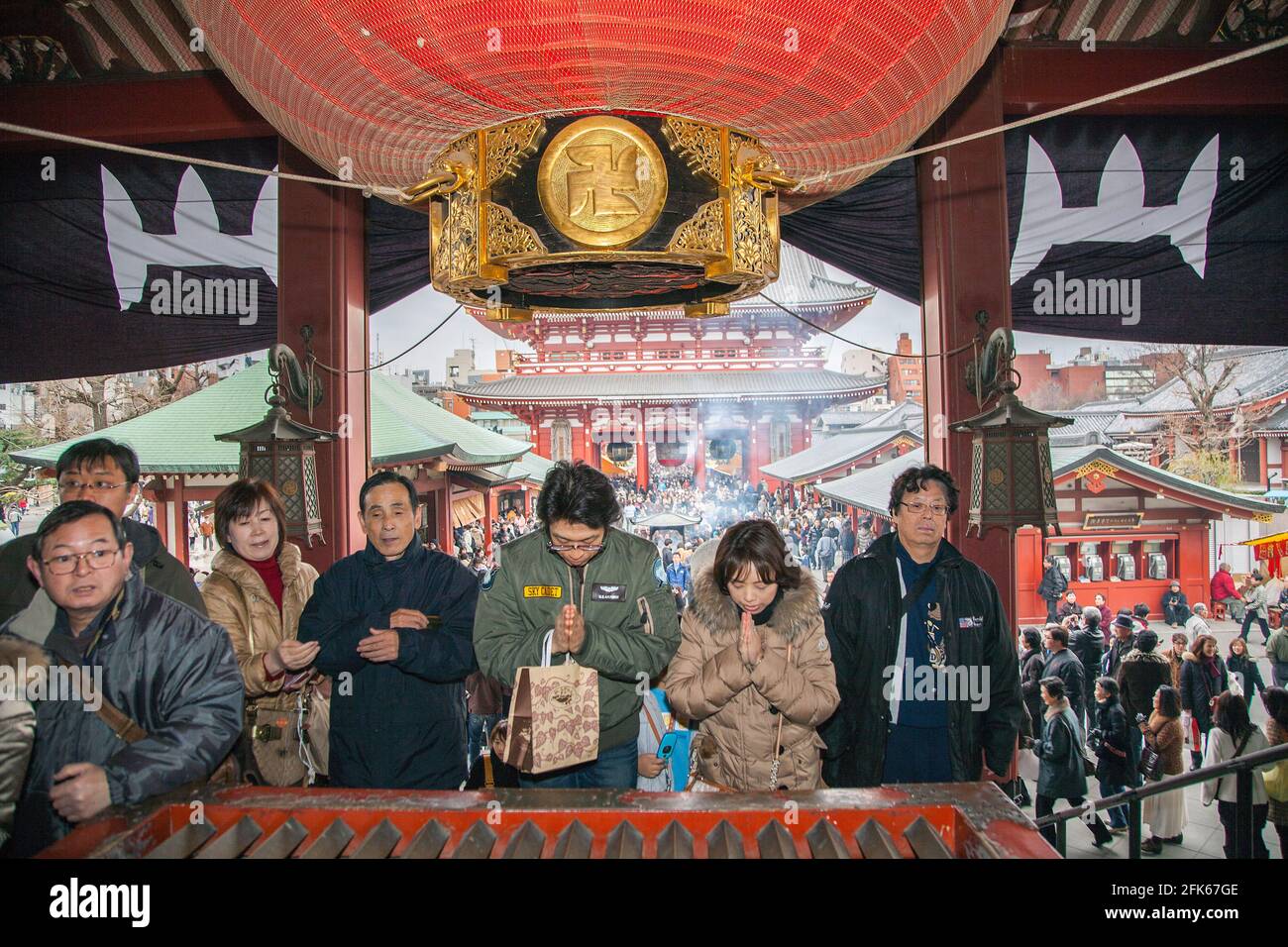 Gruppo di adoratori giapponesi in preghiera sotto l'emblema di Swastika al tempio Sensoji/浅草寺/Sensōj/Asakusa Kannon, Tokyo, Giappone Foto Stock