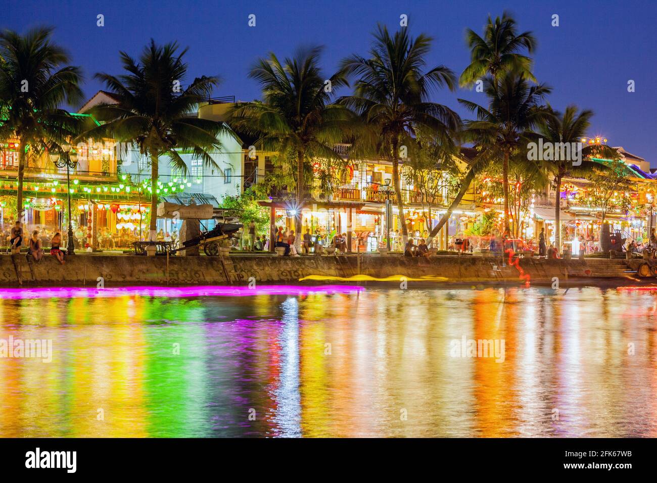 Luci colorate riflesse sull'acqua lungo il fiume nella città vecchia (riprese con una lunga esposizione lasciando sentieri di luce), Hoi An, Vietnam Foto Stock