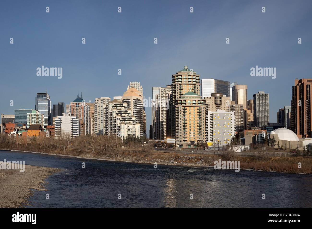 Skyline di Calgary lungo l'estremità ovest del centro con il fiume Bow in primo piano Foto Stock