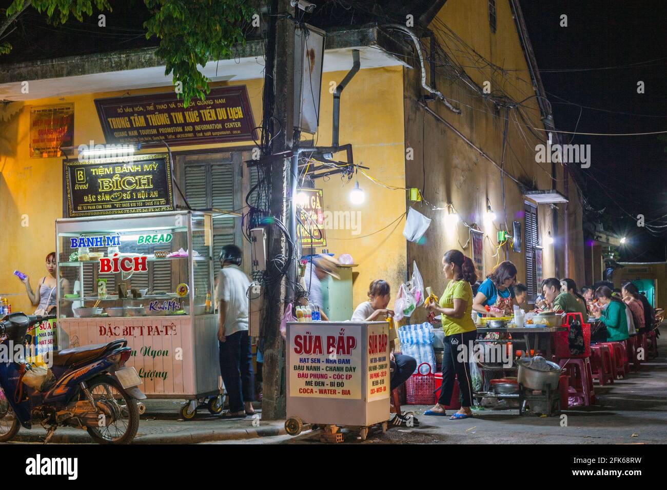 Le famiglie vietnamite si sedettero fuori la sera mangiando cibo di strada, Hoi An, Vietnam Foto Stock