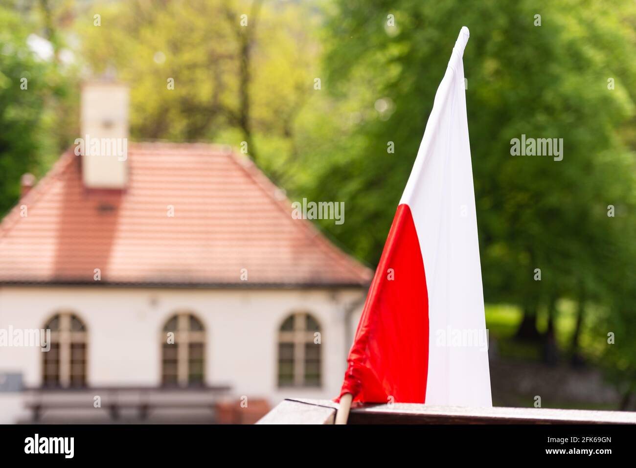 Bandiera polacca sul balcone. Bandiera bianca e rossa di fronte alla casa in Polonia. Primavera vicino a Cracovia. Foto Stock
