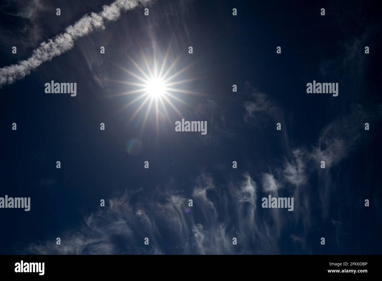 Sun Star, nuvole e jet trail Foto Stock