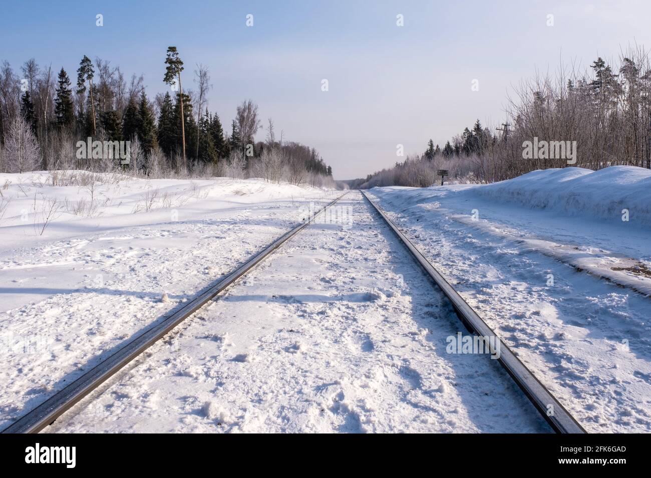 Snelle rotaie di una ferrovia ricoperta di neve bianca in una soleggiata giornata invernale, la Russia. Foto Stock