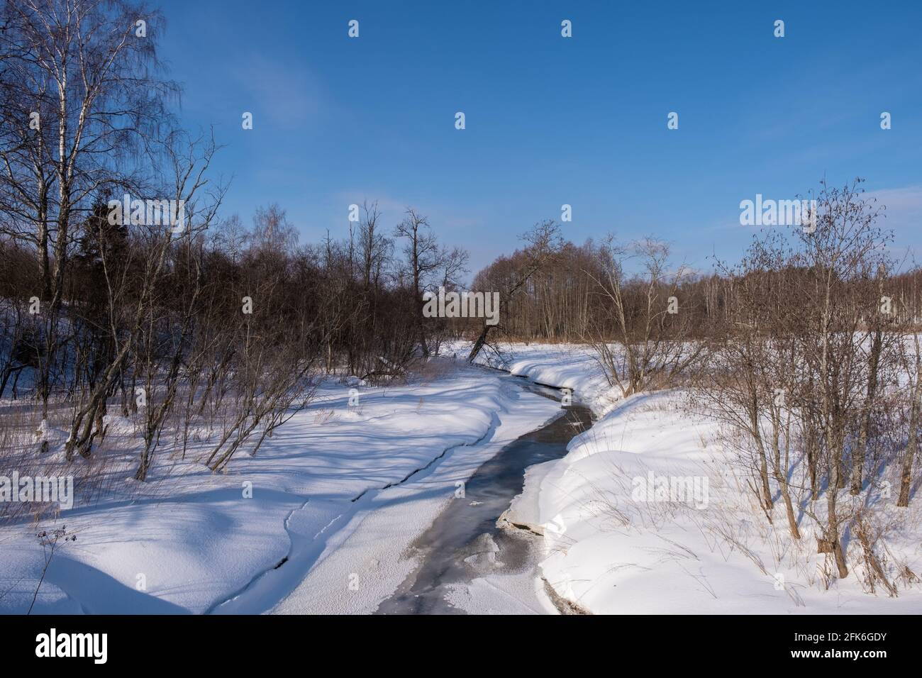 Paesaggio invernale con un piccolo fiume innevato in una giornata di sole, la Russia. Foto Stock