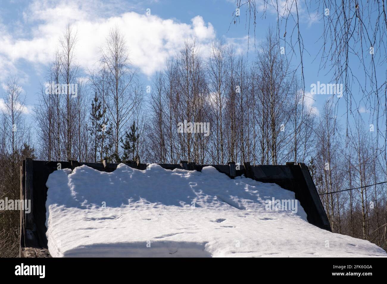 La neve bianca giace sul tetto di un piccolo fienile in una giornata di sole primavera, la Russia. Foto Stock
