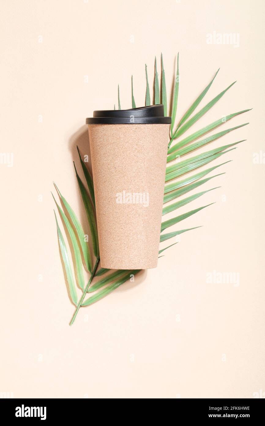 caffè ecologico riutilizzabile o tazza da tè con palmo su sfondo beige. Stile di vita sostenibile. Eco-friendly e zero rifiuti Concept.Flat lay mock up. Foto Stock