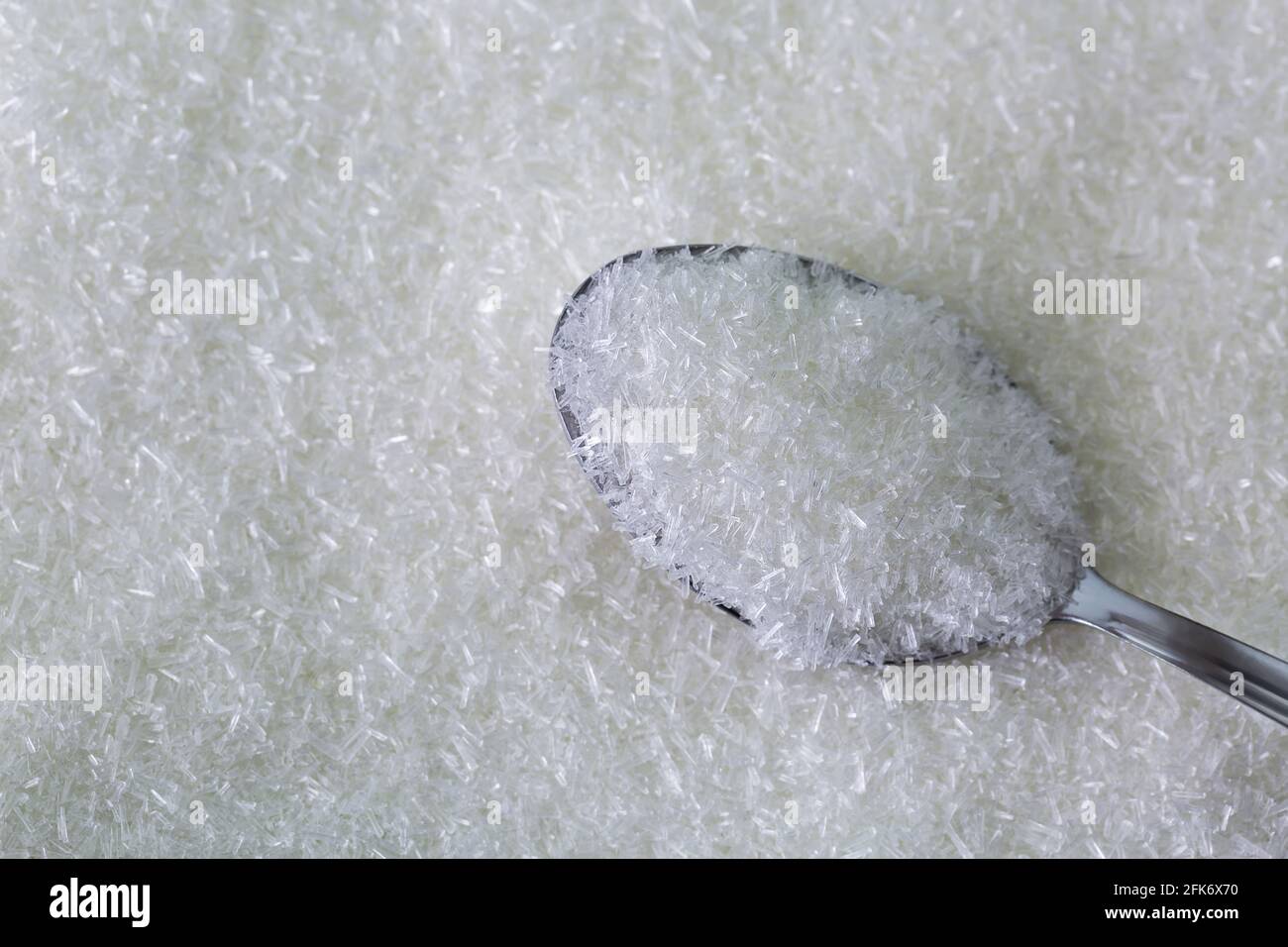 Struttura closeup di cucchiaio pieno di scaglie di MSG, glutammato monosodico, sale sodico usato come esaltatore di sapore Foto Stock