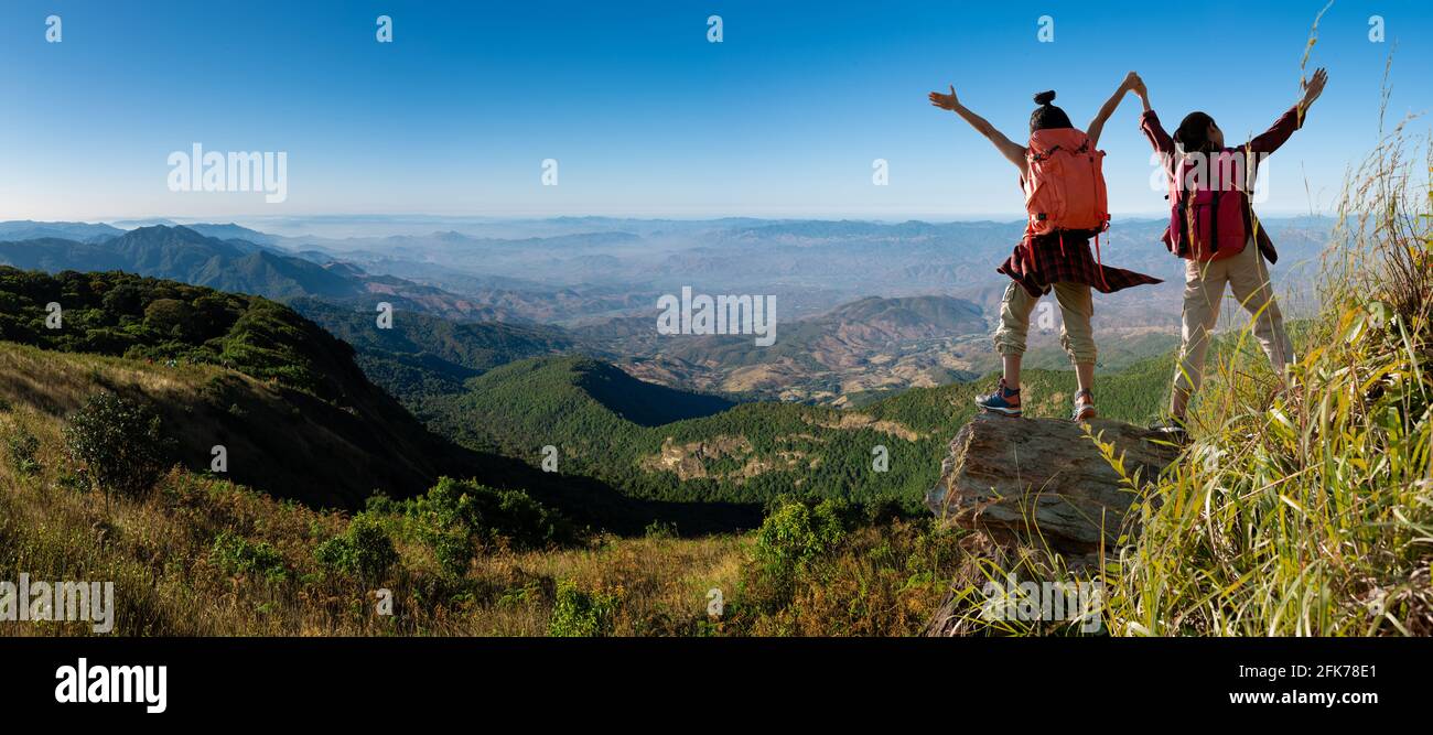 Panorama , due donne escursionisti che arrampicano sulla scogliera di montagna Foto Stock