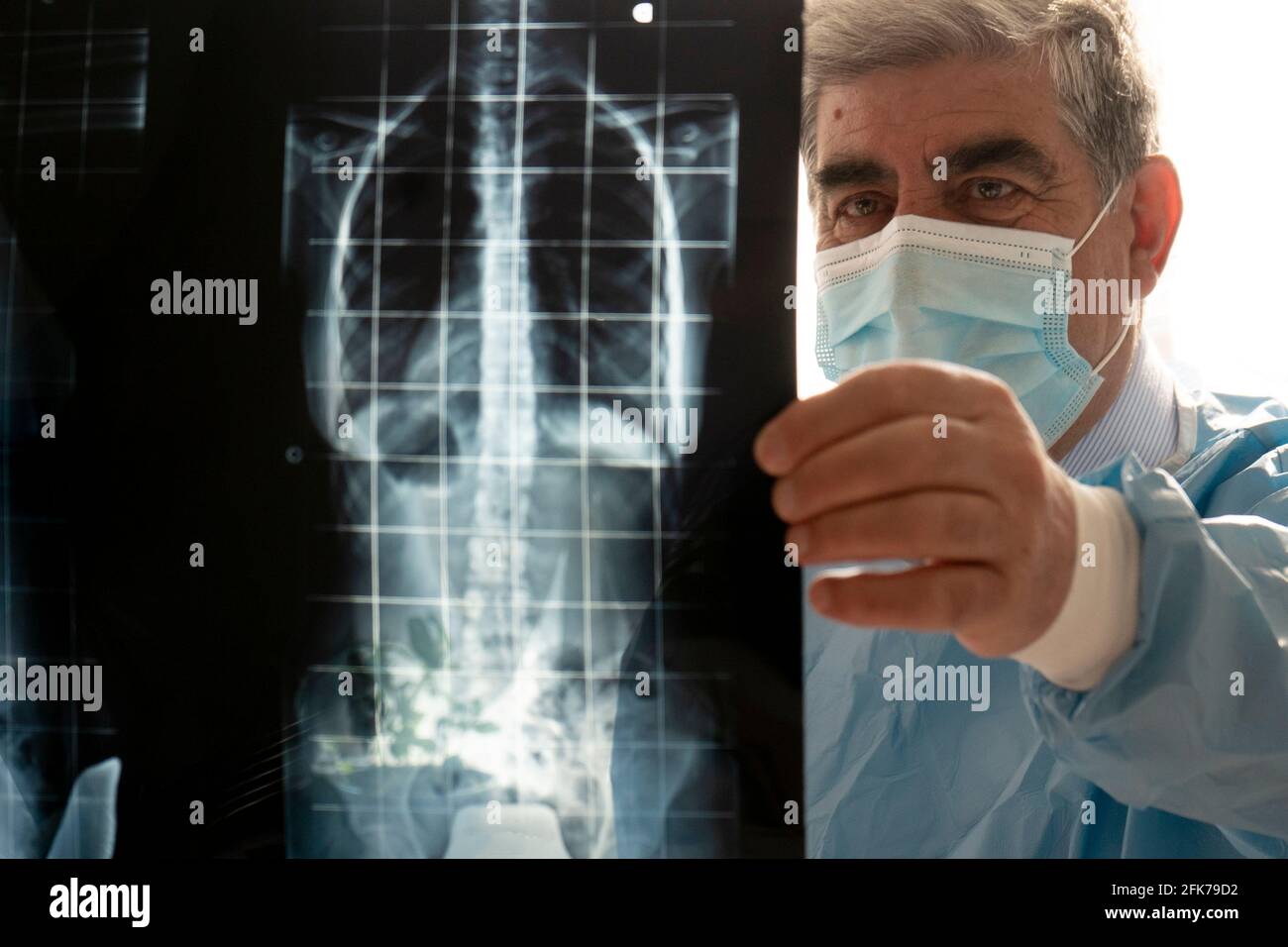 Medico maschile senior con maschera protettiva che esamina una paziente donna in ospedale, controllando i raggi X. Foto Stock