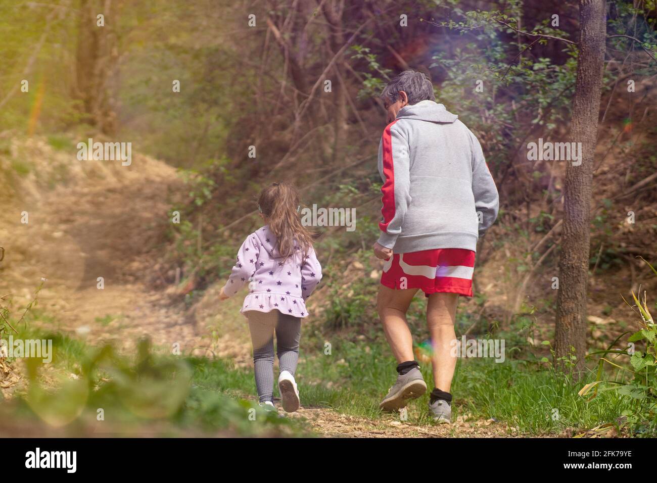 Nipote corre con suo nonno per aiutarlo a tornare in forma. Corsa al tramonto. Foto Stock