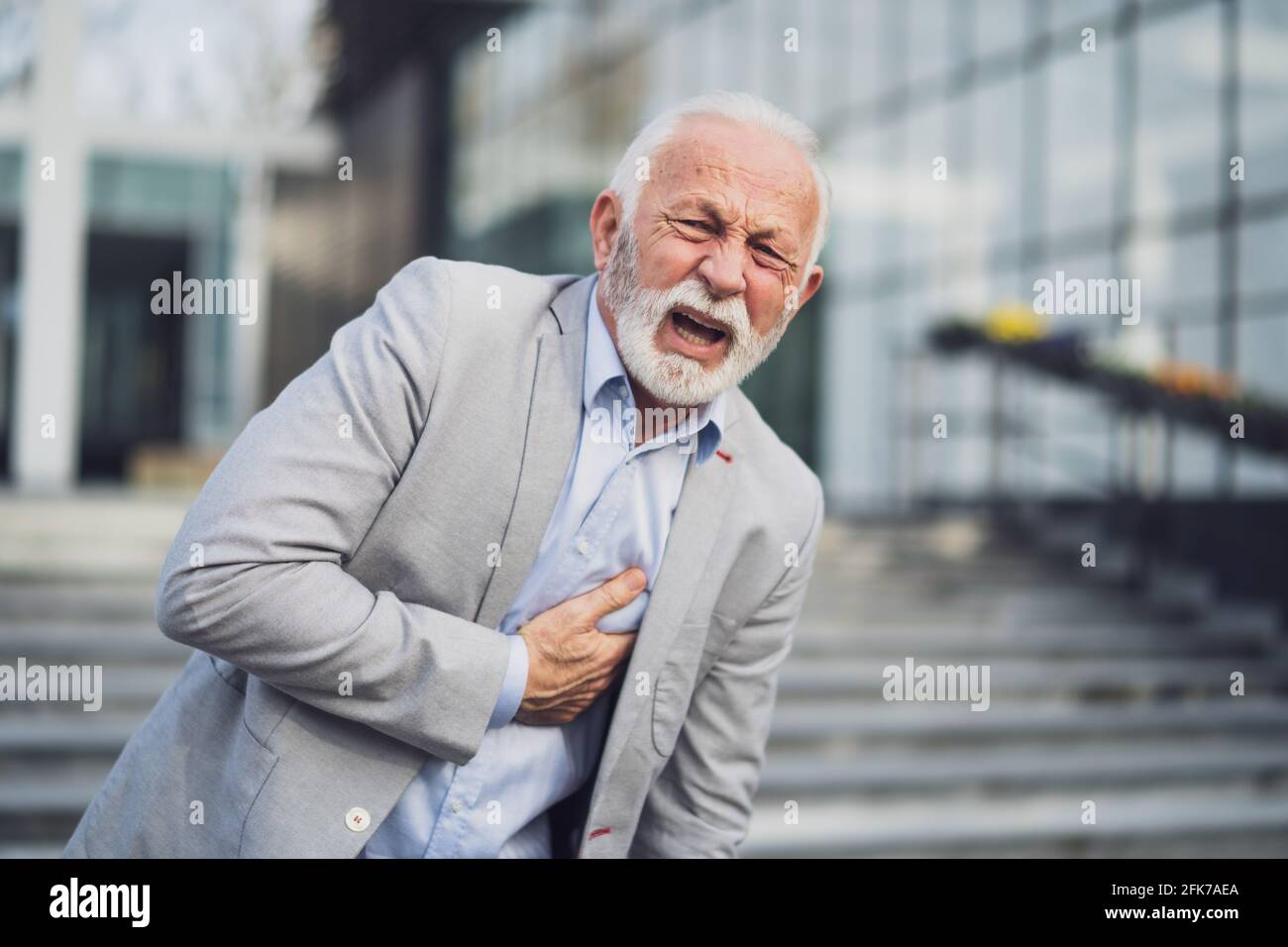 L'uomo d'affari anziano sta avendo colpo davanti alla costruzione dell'azienda. Foto Stock