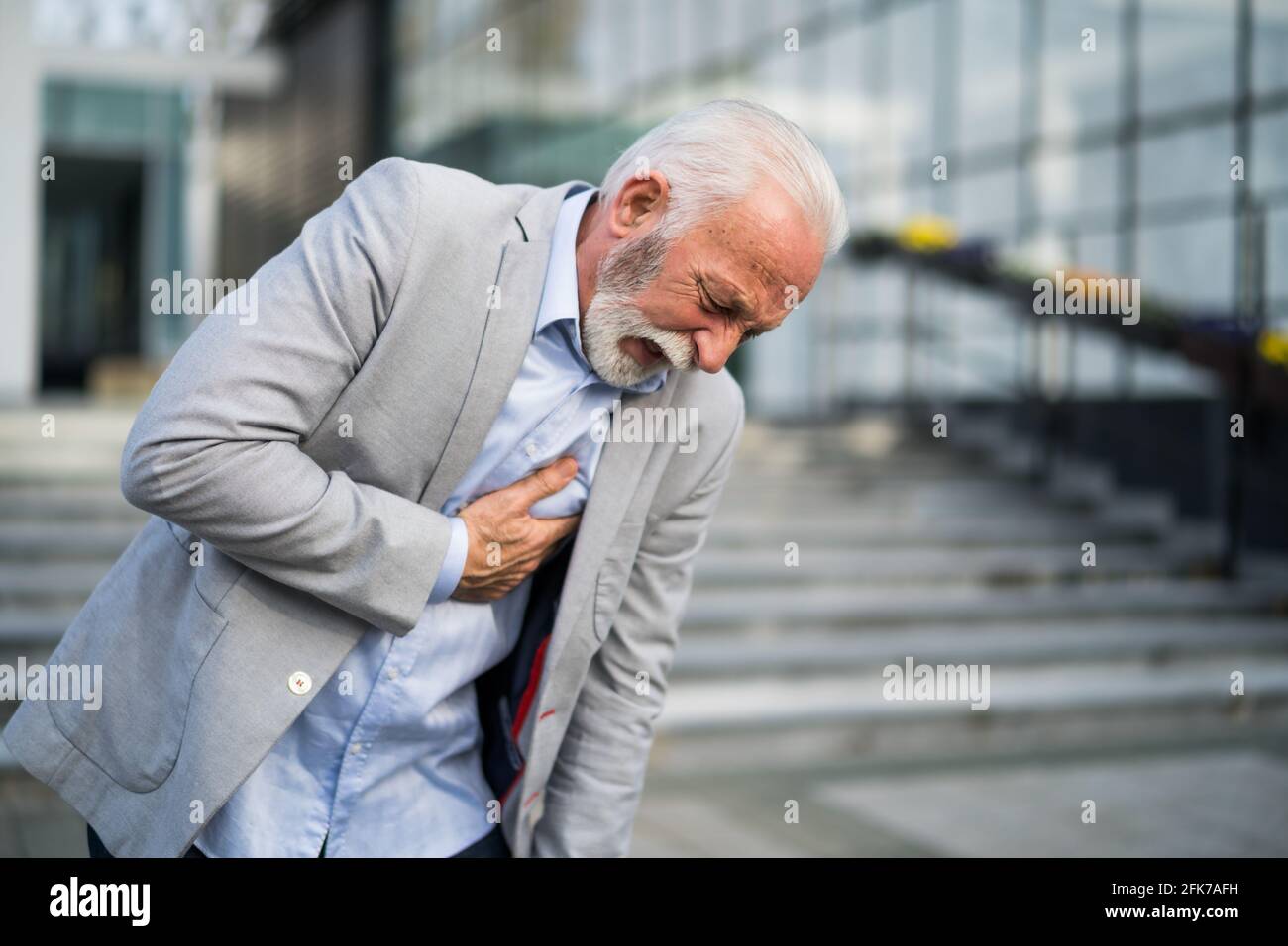 L'uomo d'affari anziano sta avendo colpo davanti alla costruzione dell'azienda. Foto Stock