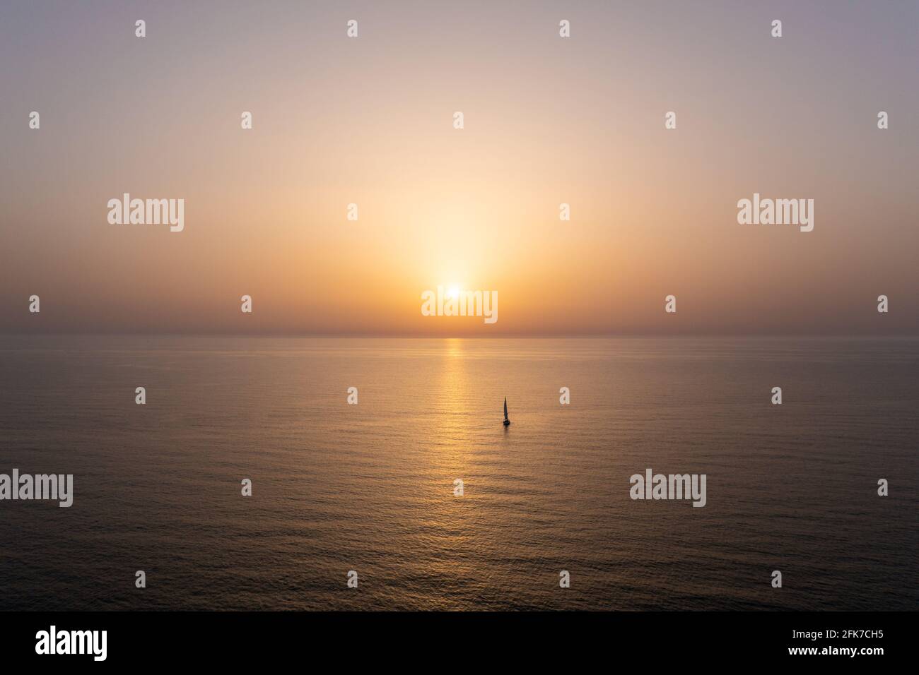 Vela barca a vela lentamente verso un tramonto sole nel Mar Mediterraneo. Foto Stock