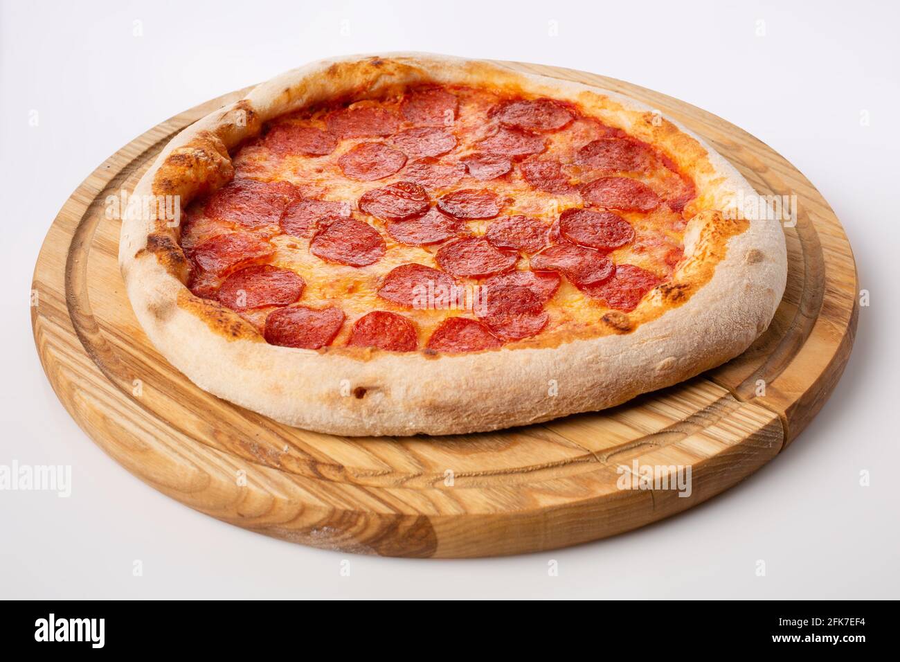 Vista dall'alto della pizza calda su un piedistallo in legno. Pizza pepperoni. Base di pomodoro, due tipi di formaggio e molto salame. Foto Stock