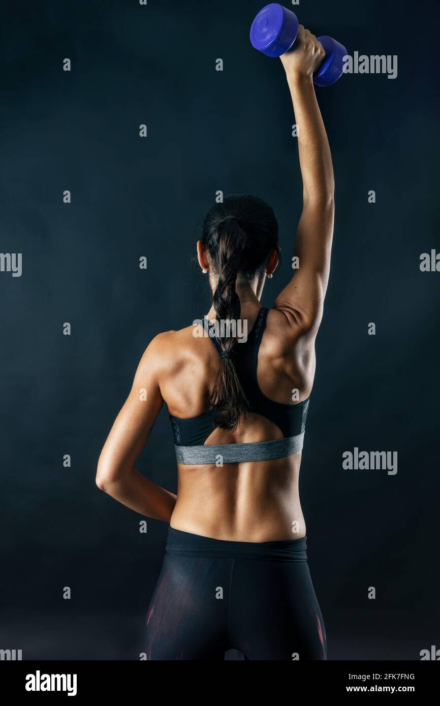 Donna che esegue esercizi di fitness isolato su sfondo scuro. Foto Stock