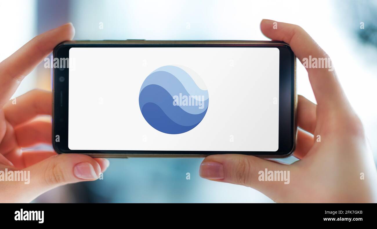 POZNAN, POL - Apr 25, 2021: Smartphone con mani che mostra il logo di Google Earth, un programma per computer, che rende una rappresentazione 3D di Earth ba Foto Stock