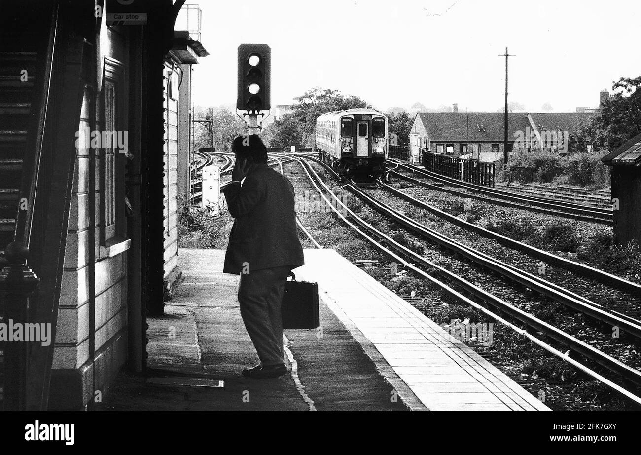 Stazioni ferroviarie Clapham Junction un uomo parla sul suo cellulare il telefono come un treno pendolari adopra la piattaforma dbase Foto Stock