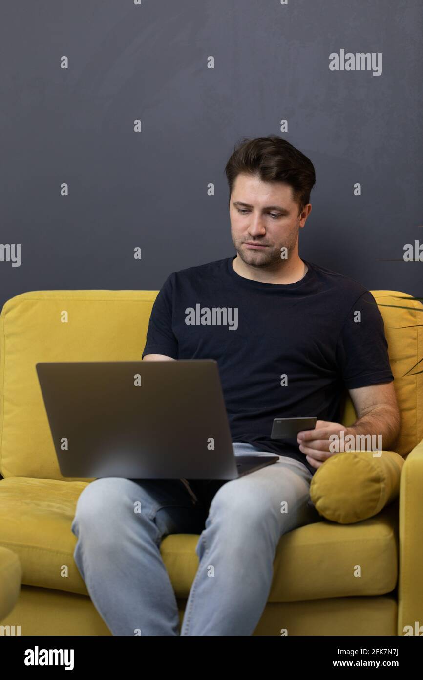 guy effettua acquisti o pagamenti online, guarda il codice di sicurezza cvv della carta di credito Foto Stock