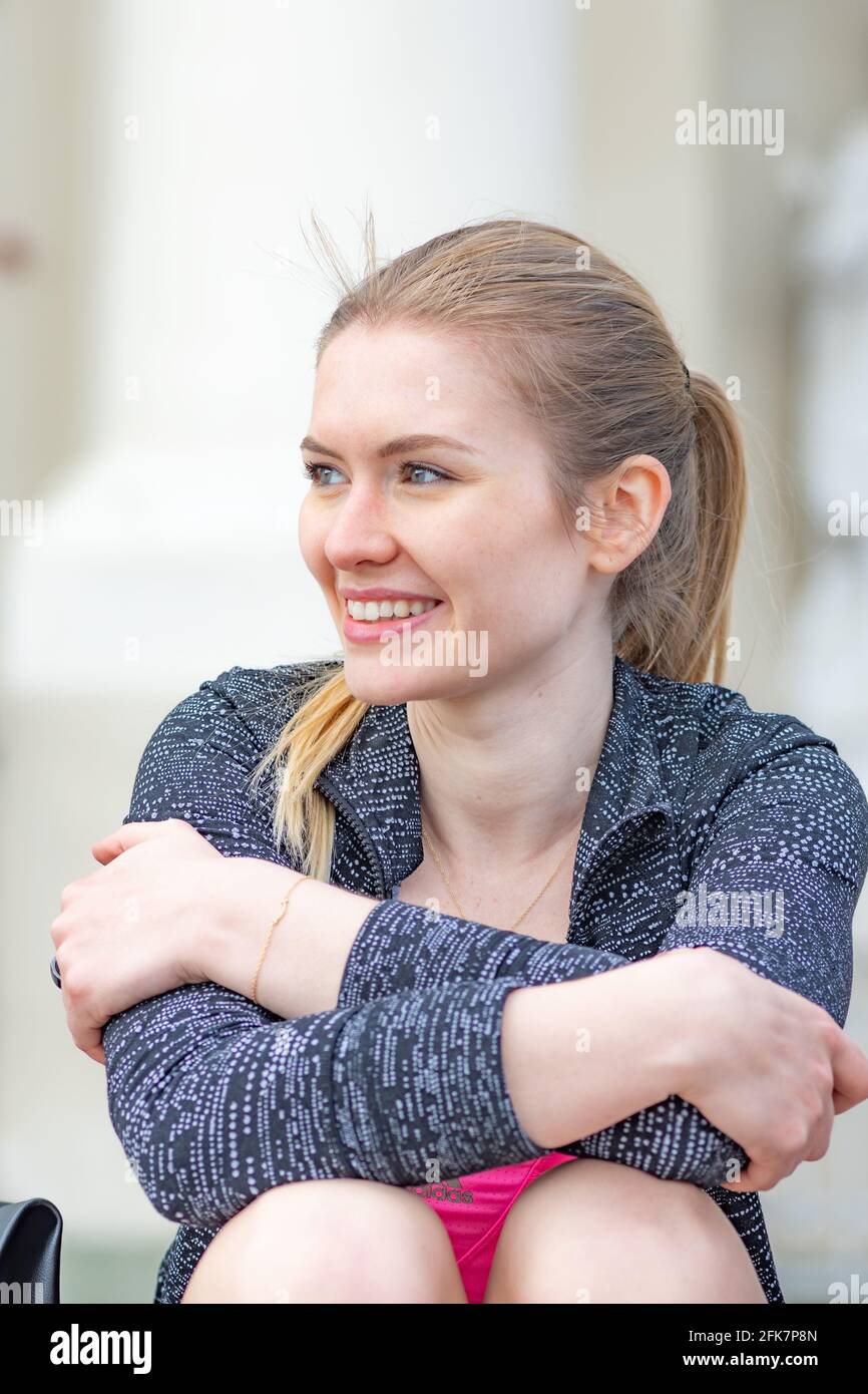 Ritratto di bella giovane bella ragazza bionda sorridente e godendo il bel tempo e la vita in città, verticale Foto Stock