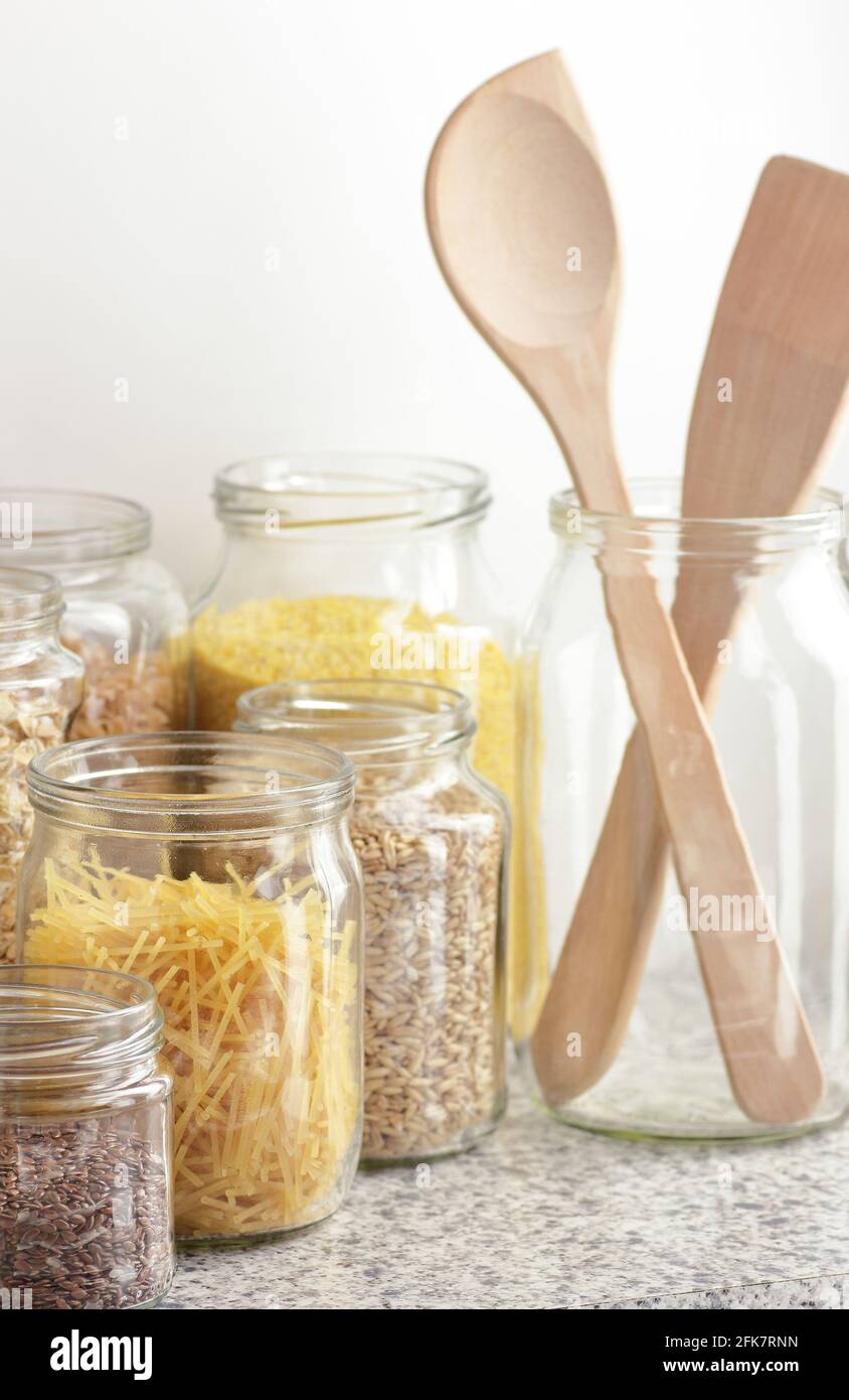 Varietà di cereali, cereali, pasta, semi in vasetti di vetro non cotti su fondo bianco della cucina, closeup, rifiuti zero, eco-friendly, alimentazione a dieta equilibrata, lui Foto Stock