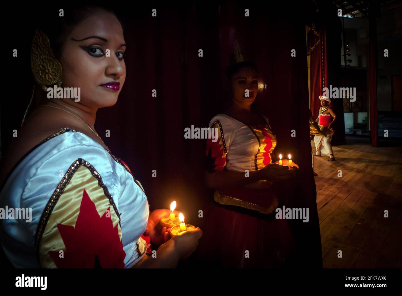 Kandy, Sri Lanka: Un ballerino della Kandyan Arts Association si nasconde dietro il sipario prima di entrare nel palco per lo spettacolo serale Foto Stock