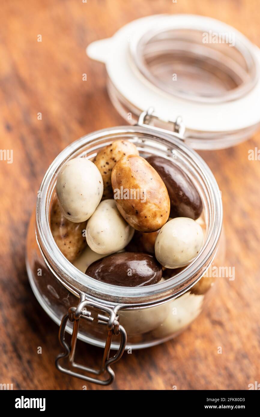 Mandorle dolci al cioccolato in vaso. Uova di cioccolato su tavolo di legno. Foto Stock