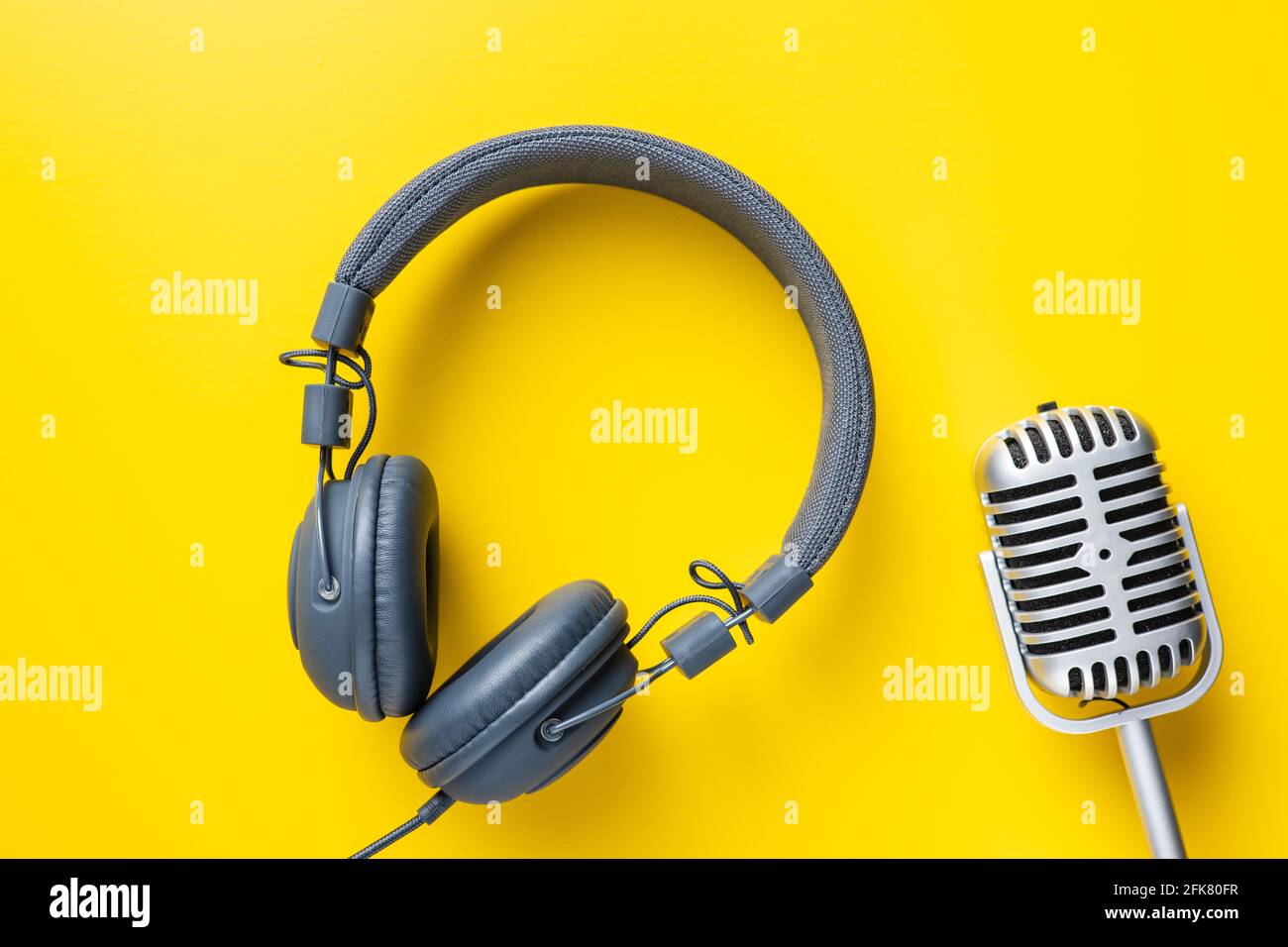 Microfono e cuffie vintage su sfondo giallo. Vista dall'alto. Foto Stock