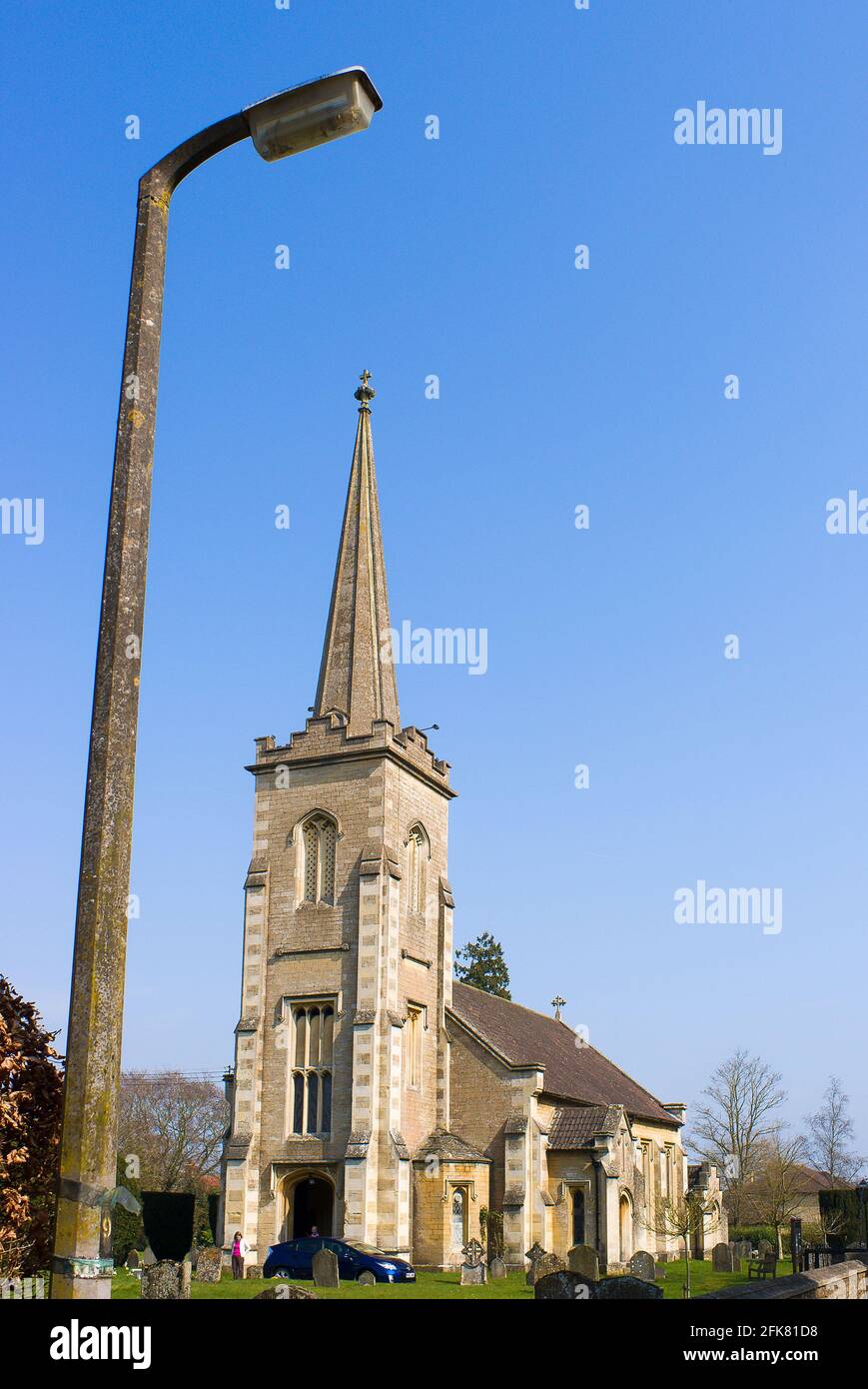 Un'illusione che suggerisce che una lampada da strada è più alta di Una guglia di chiesa nel Regno Unito Foto Stock