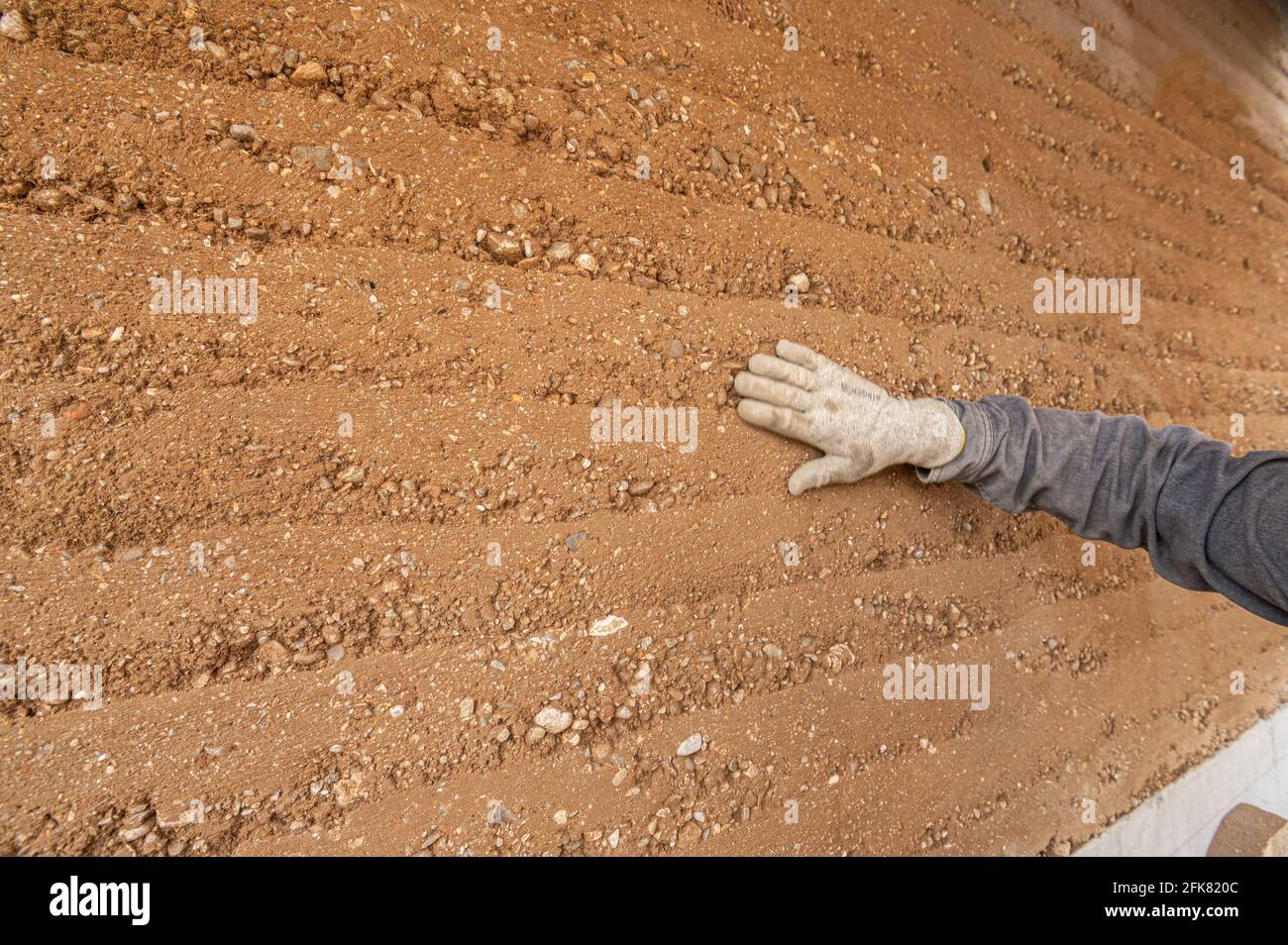 Lavoratore di costruzione che controlla la costruzione di muro di terra ramped! Foto Stock