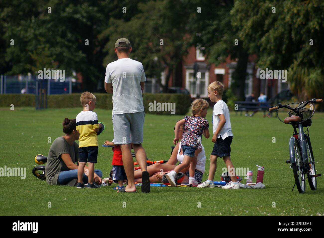 Una famiglia con bambini che si rilassa nel parco locale in una giornata calda in estate con sfondo sfocato. Foto Stock