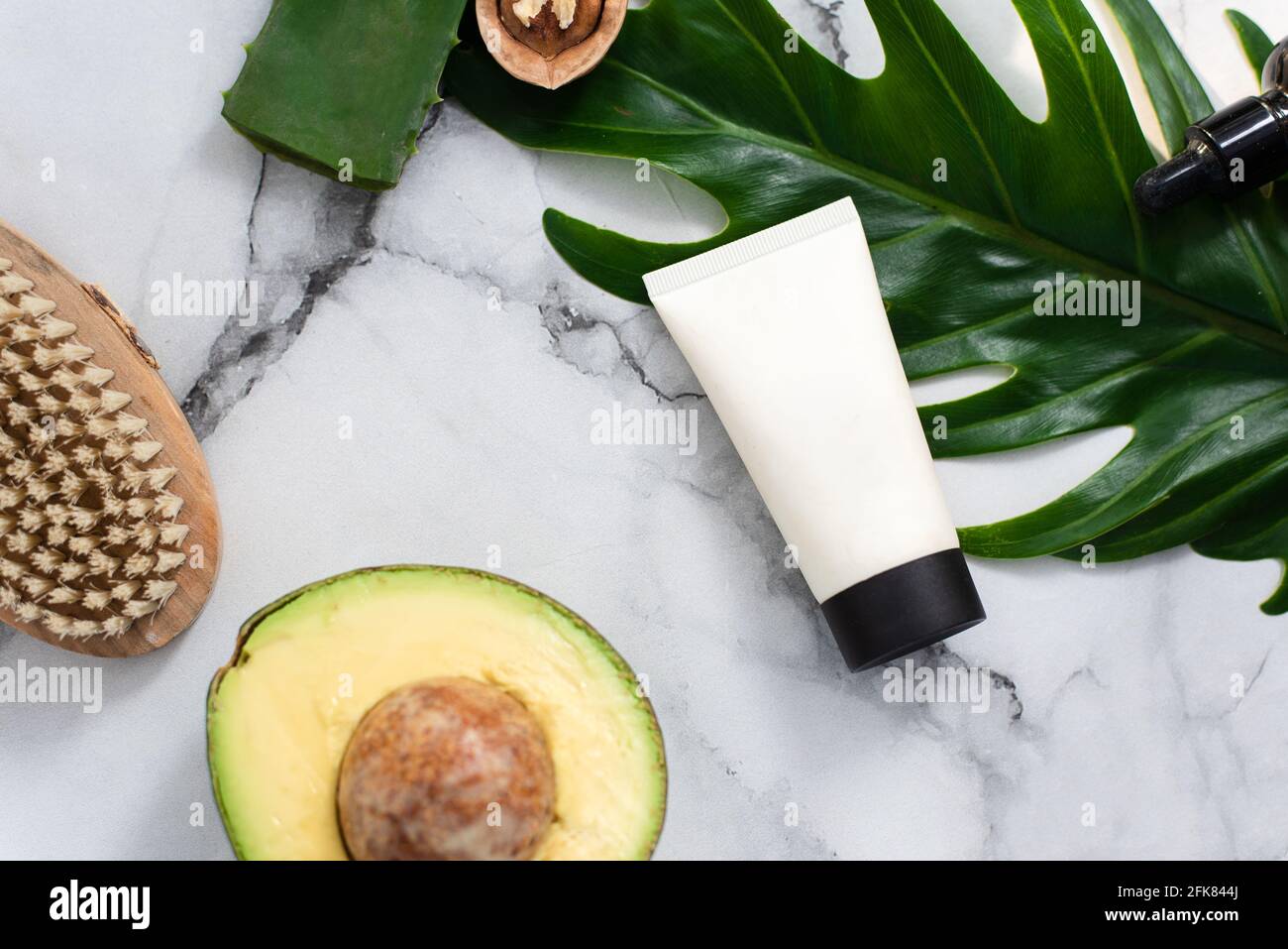 Una bella composizione con olio, sapone scarlatto, avocado e noci. Bottiglie con prodotti cosmetici spa su sfondo a foglia di palma, vista dall'alto. Salone di bellezza Foto Stock