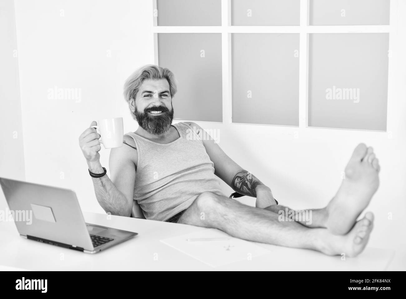 bearded uomo bere caffè e lavorare con comfort. auto formazione online. soggiorno a casa. blocco sulla quarantena coronavirus. lontano business. barefoot Foto Stock